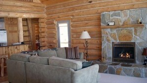 A log cabin interior with a stone fireplace, a sofa, and a ladder. - Special Labor Day Weekend! The cabin is available for 6-8 guests in 3 bedrooms. (Longville)