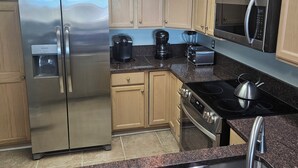 A modern kitchen with a stainless steel refrigerator, a microwave, a stove, and a coffee maker.