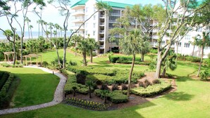A hotel with a well-maintained garden, a gazebo, and a view of the ocean.