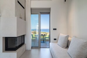 Un salon moderne avec un canapé, une cheminée et une porte-fenêtre coulissante donnant sur un espace extérieur aménagé avec une table et des chaises.
