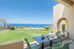 A patio with a table and chairs overlooking a pool and ocean view. - Seafront luxury apartment with amazing sunset view 4 (Stavros, Chania)
