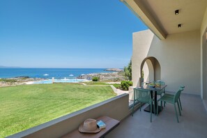 Un balcon avec vue sur la mer, une piscine et une table avec des chaises.