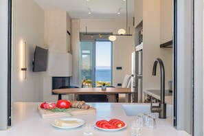 Une cuisine moderne avec vue sur la mer, un coin repas et un téléviseur à écran plat.