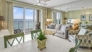 A spacious living room with a balcony, a dining area, and a sofa set. - 1 Bedroom Beachfront Condo Sleeps 6 (Destin)