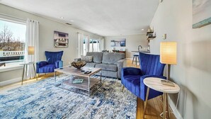 Un salon moderne comprenant un canapé, des fauteuils, une table basse et un coin repas.
