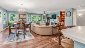 A spacious living room with a large curved sofa, a dining area with wooden chairs, and a fireplace. - Waterfront 4 Bed 3 Bath Sleeps 8 - Free River Cruise with Week Long Rental (Heathsville)