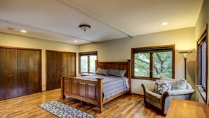 A bedroom with a wooden bed, a wooden wardrobe, a sofa, and a window with a view of trees. - Fabulous Minneapolis Townhome--Large Groups (Minneapolis)
