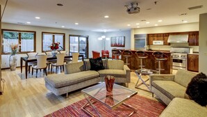 A modern living room with a dining area, kitchen, and large windows. - Fabulous Minneapolis Townhome--Large Groups (Minneapolis)