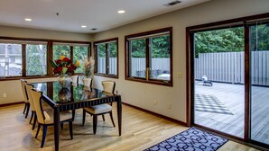 A dining area with a glass-top table, six chairs, and a vase with flowers. - Fabulous Minneapolis Townhome--Large Groups (Minneapolis)