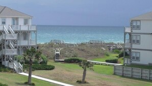 Une propriété située en bord de mer, offrant une vue sur l’océan, comprenant une maison à plusieurs niveaux dotée d’un balcon et un bâtiment séparé également pourvu d’un balcon.