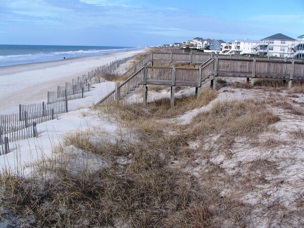 Une plage avec des promenades en bois qui mènent à un quartier résidentiel bordé de maisons.