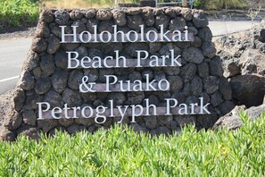 A stone sign with the text "Holoholokai Beach Park & Puako Petroglyph Park".