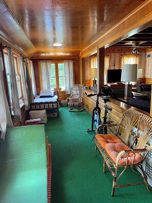 A room with a bed, a desk, a chair, a television, and a window with curtains.