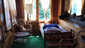 A cozy cabin interior with a bed, two wicker chairs, a small table, and a sofa. - Papa’s Lake House, Quiet Retreat, Main Part Of Greater Bass Lake , Sleeps 12-14 (Greater Bass Lake)