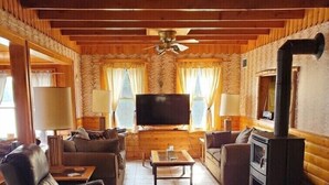 A cozy living room with a fireplace, sofas, a TV, and a ceiling fan. - Papa’s Lake House, Quiet Retreat, Main Part Of Greater Bass Lake , Sleeps 12-14 (Greater Bass Lake)