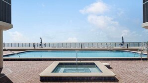 En pool på taget med krystalklart havudsigt, liggestole og et spabad.