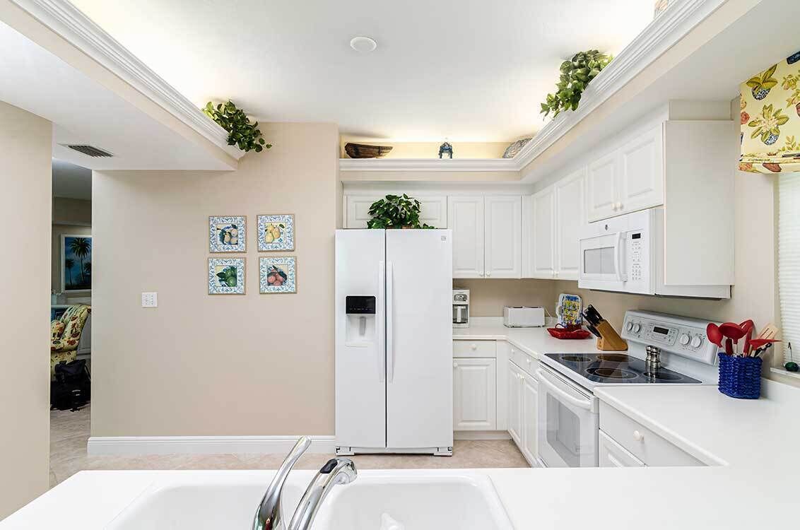 A modern kitchen with white cabinetry, a refrigerator, a microwave, and a stove.