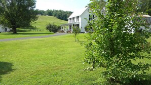 A white building with a porch, surrounded by a well-maintained lawn and trees. - Peace, quiet & relaxation!  Family friendly home. (Sugar Grove)