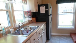 A kitchen with a sink, countertop, cabinets, a refrigerator, and a window with curtains. - Peace, quiet & relaxation!  Family friendly home. (Sugar Grove)