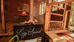 Interior rústico de una cabaña con un letrero que dice 'Lazy Squirrel' y una figura de oso en un estante de madera.