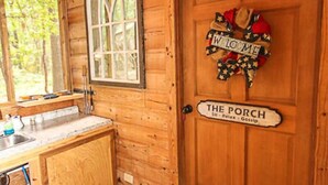 Un interior de madera con una puerta que dice “THE PORCH” y un cartel de bienvenida.