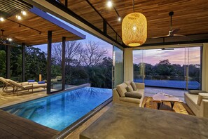 Un área exterior moderna con piscina, mobiliario y amplios ventanales que ofrecen vistas del paisaje circundante.