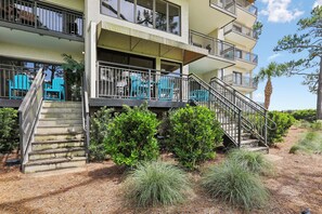 A multi-story hotel with balconies, outdoor seating, and a staircase leading to the entrance.