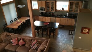 A cozy living room with a brown sofa, a dining table, and a kitchen area with wooden cabinets and a black countertop.