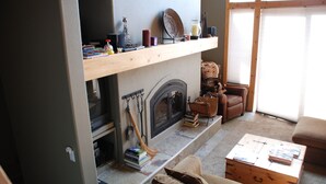 A cozy living room with a fireplace, a bookshelf, and a comfortable seating area.