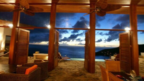 Ein Zimmer am Strand mit Blick auf das Meer, Holzboden und Deckenventilatoren.