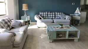 A living room with a striped sofa, a blue accent wall, and a coffee table with decorative items. - Newly Renovated Coastal Style house (Sebastian)