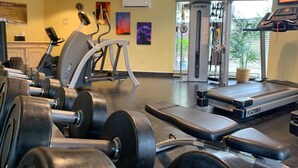 Un gimnasio con cintas de correr, máquinas de pesas y pesas libres.