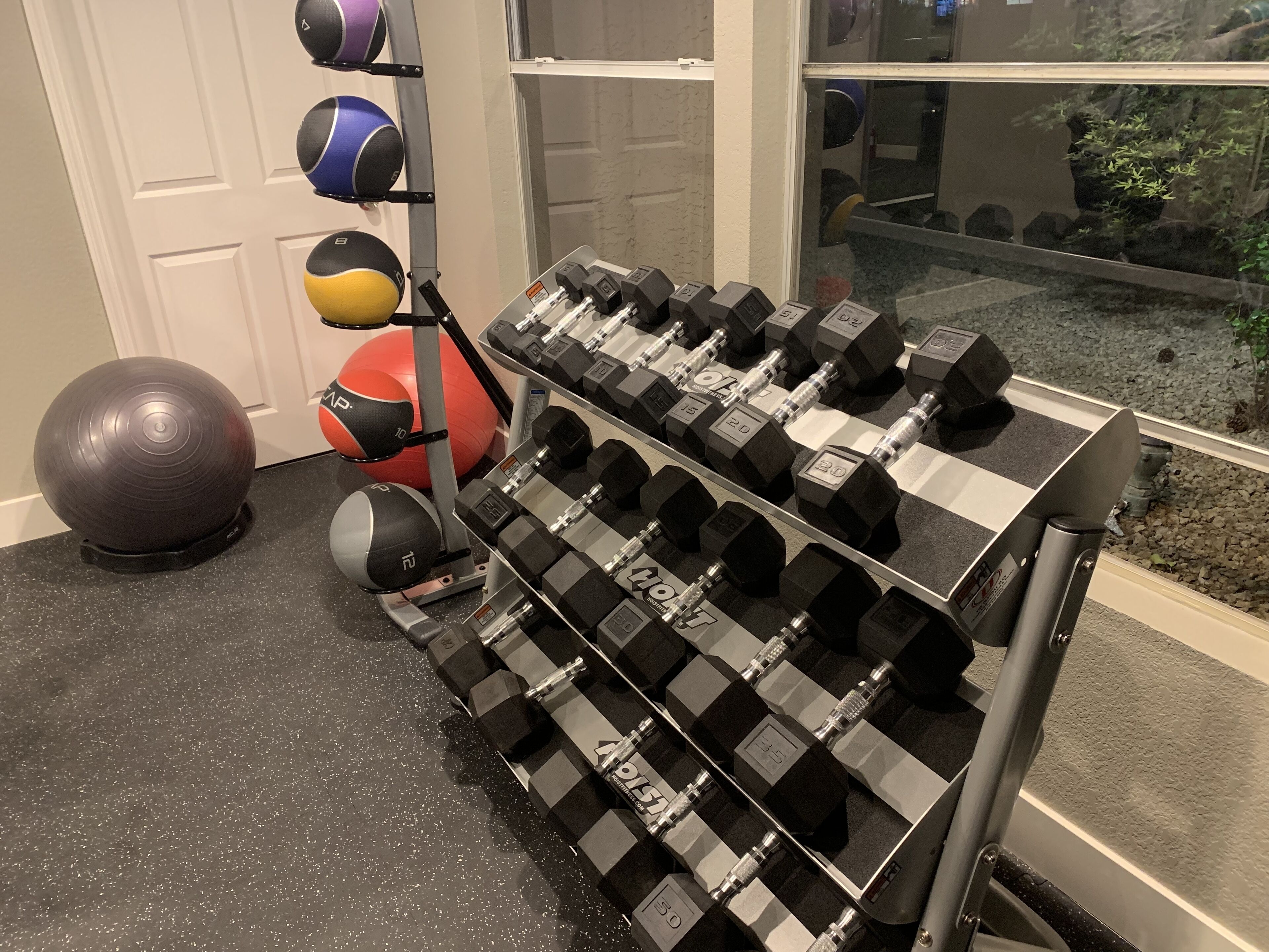 Un gimnasio en casa con diversos equipos de ejercicio, incluyendo mancuernas, un balón medicinal y una bicicleta estática.