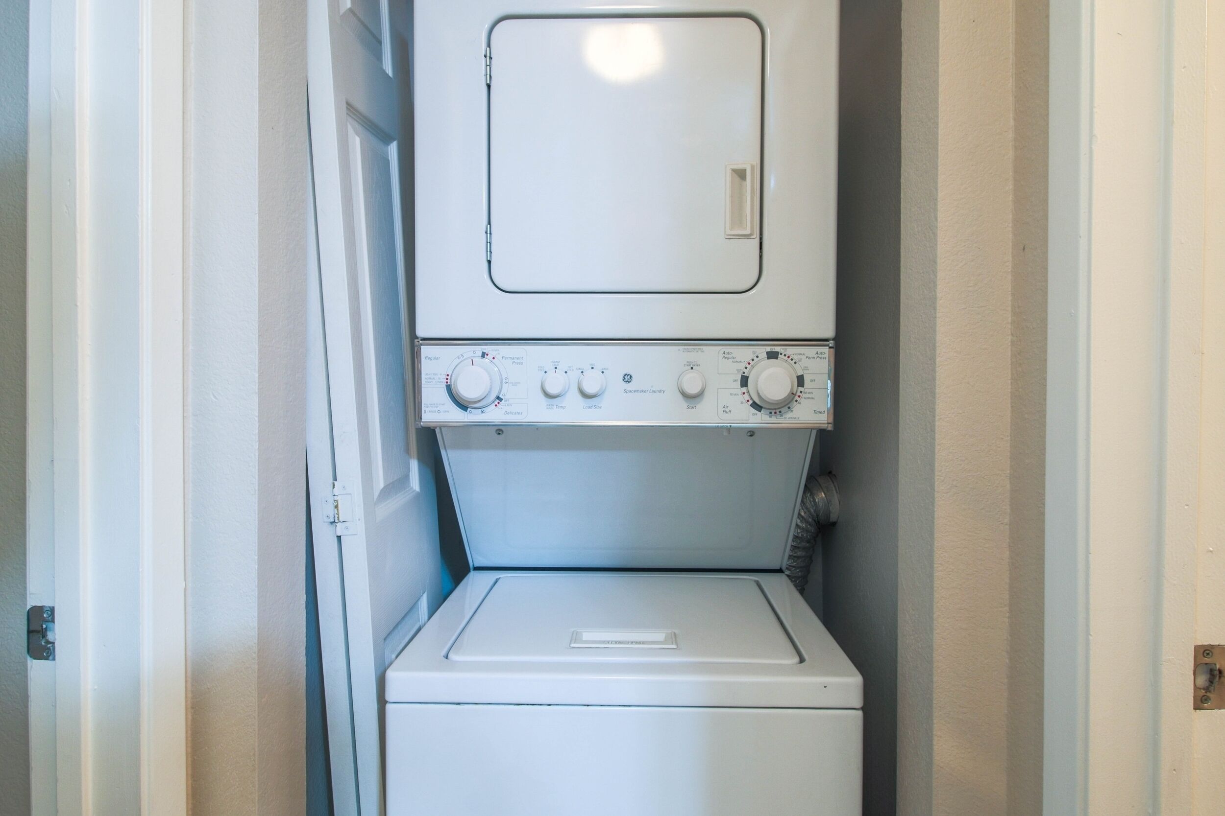 Uma lavanderia compacta e branca, com máquina de lavar frontal e secadora.