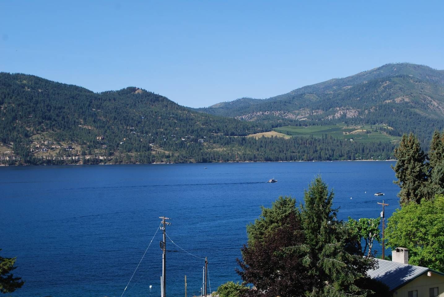 A lake with a boat, surrounded by mountains and trees.