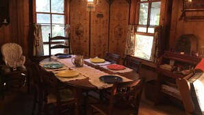 A wooden dining room with a table set for four, surrounded by chairs. - Family & dog friendly; walk to beach, cliff, town, ferries, all bedrooms w/AC (Oak Bluffs)