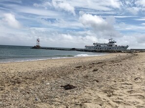 A beach with a rocky shore, a lifeguard tower, and a large boat named 'Island Queen' anchored near the shore. - Family & dog friendly; walk to beach, cliff, town, ferries, all bedrooms w/AC (Oak Bluffs)