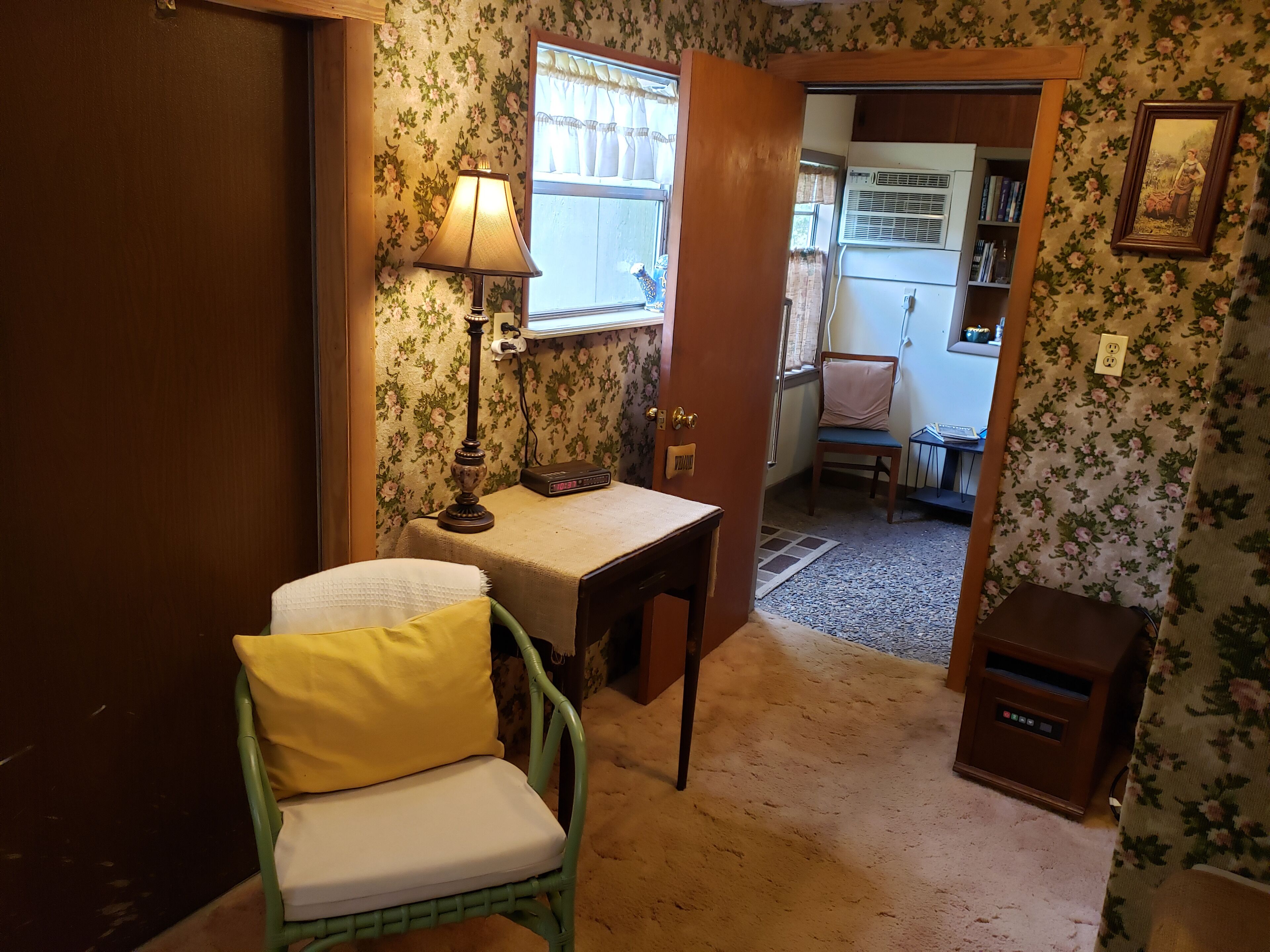 A cozy room with a green chair, a small table, a lamp, and a window with curtains.