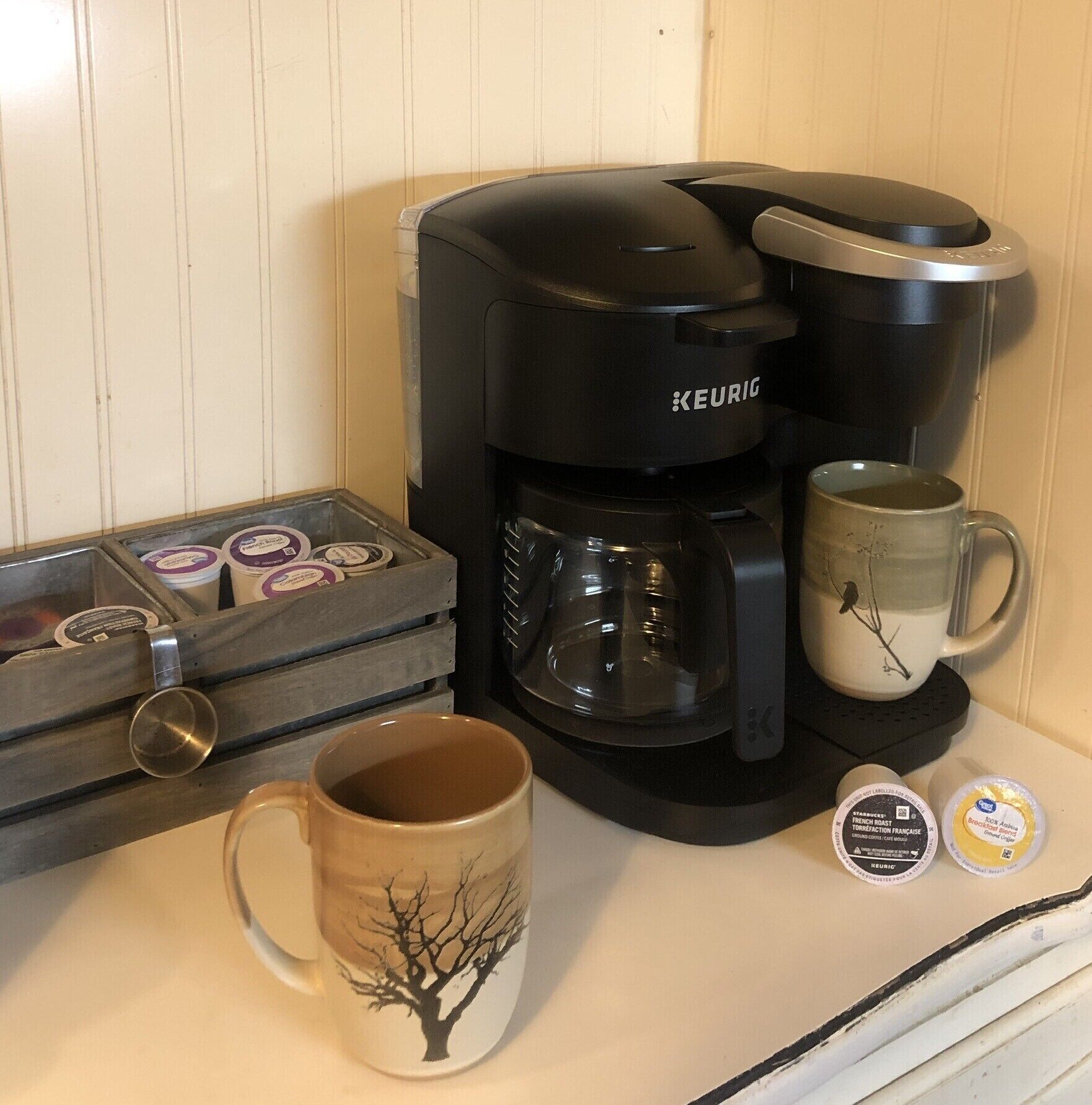 A Keurig coffee maker with a mug and coffee pods on a kitchen counter.
