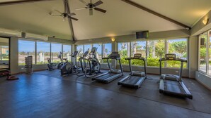 A gym with treadmills, elliptical machines, and a ceiling fan. - RELAXING and classic best BEACHFRONT condo. (Noord)