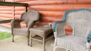 Wicker chairs and a table outside a log cabin. - The Cabin at Panther Valley Ranch (Hot Springs)
