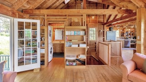 A rustic wooden interior with a laundry area, bookshelves, and a cozy seating area. - Sunset House: Rustic Maine Cottage Perched High Above Fishing Village with Harbor Views (Port Clyde)