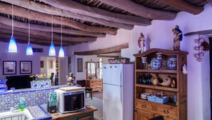Una cucina rustica con travi a vista in legno, un frigorifero bianco e un mobiletto in legno decorato con piatti.