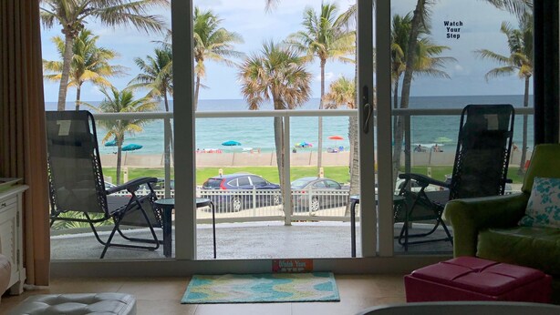 Une chambre avec vue sur la plage, comprenant deux fauteuils et une petite table.