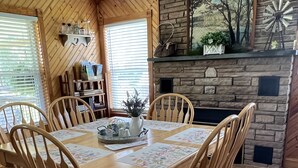 A dining room with a wooden table and chairs, a fireplace, and a bookshelf.