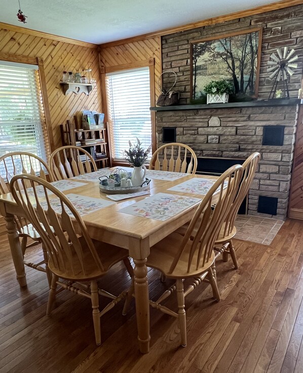 Un comedor con una mesa y sillas de madera, una chimenea y una estantería.