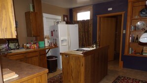 Eine kompakte Küche mit Holzausstattung, einem Kühlschrank, einer Spüle und einer kleinen Kücheninsel.