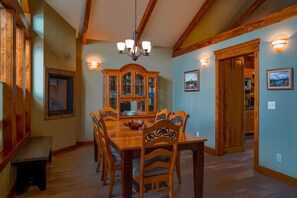 A dining area with a wooden table and chairs, a chandelier, and a cabinet with glass doors.