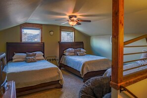 A bedroom with two beds, a ceiling fan, and a window.