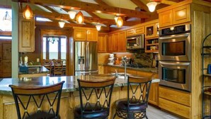 A spacious kitchen with wooden cabinets, stainless steel appliances, and a central island with bar stools.